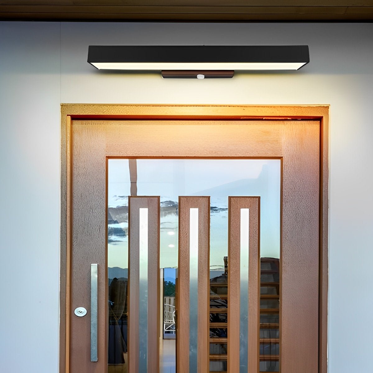 Modern wooden door with glass panel and decorative elements, illuminated by a wall-mounted light fixture.